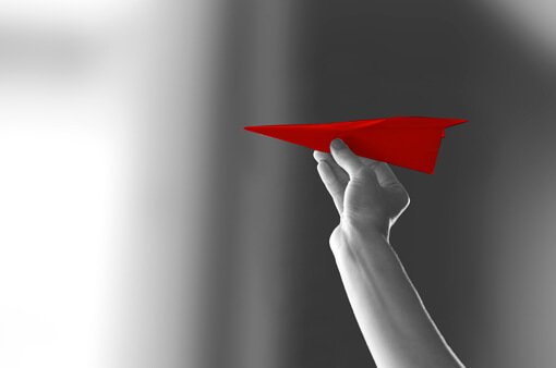 Main tenant un avion en papier rouge